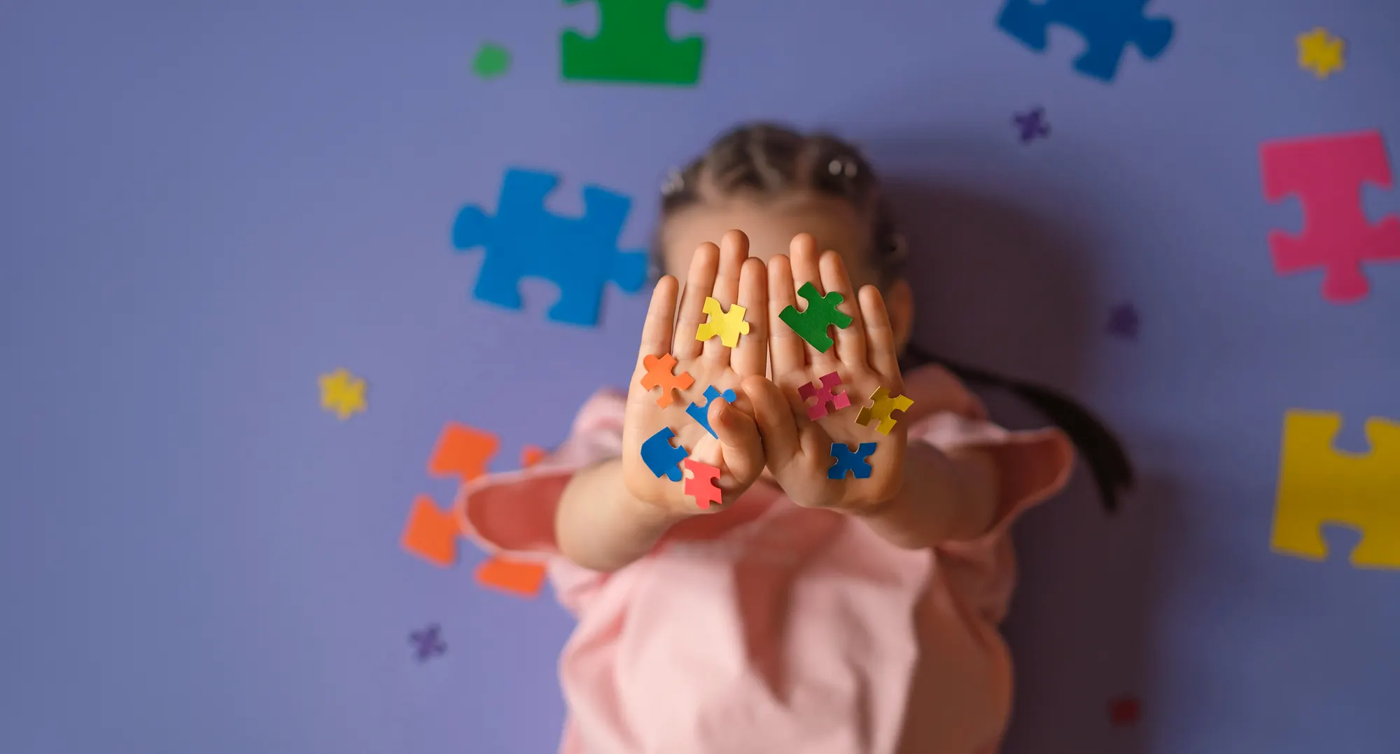 Child holding up both palms covered in colourful jigsaw-piece stickers