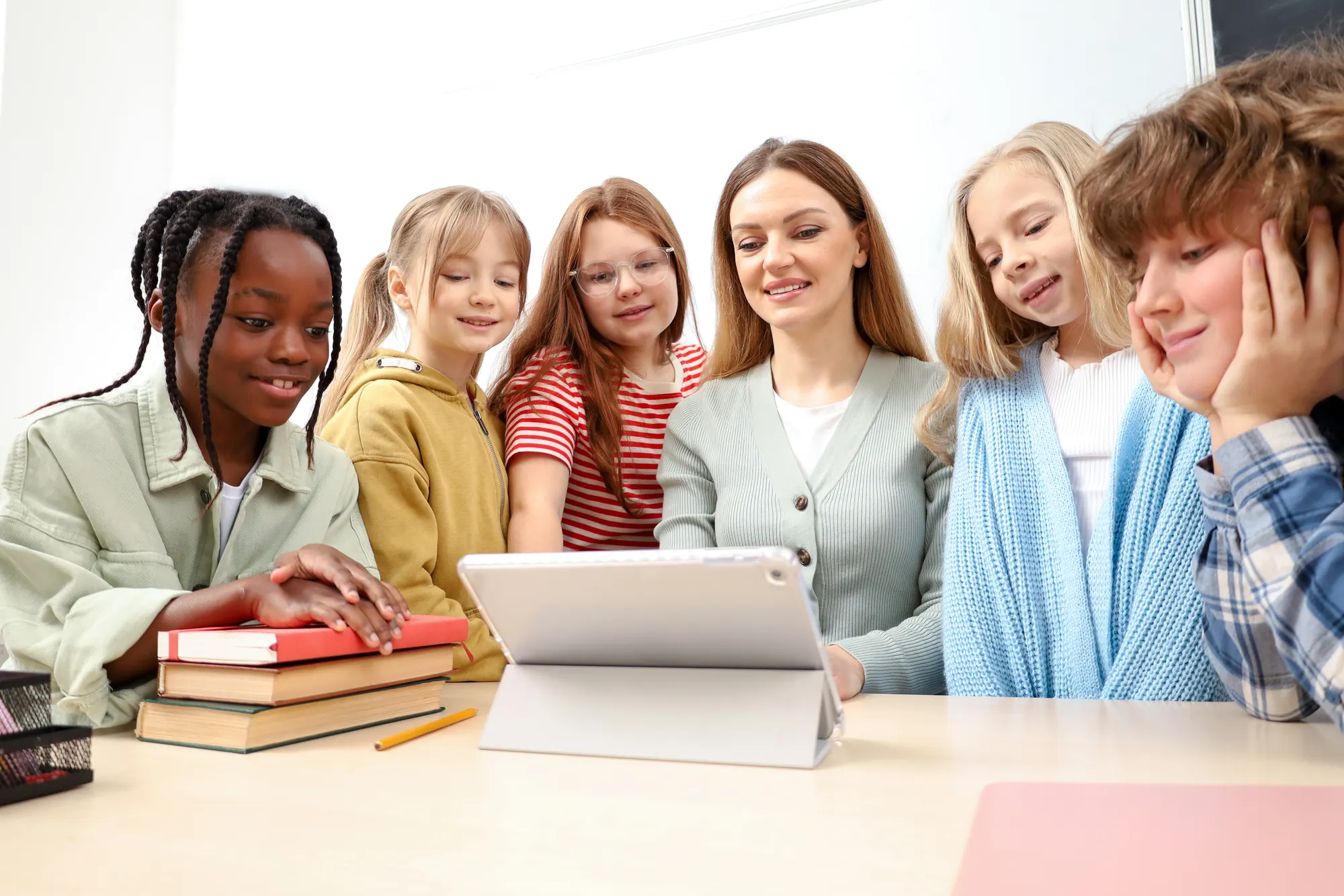 Teacher and a group of pupils gathered round a tablet