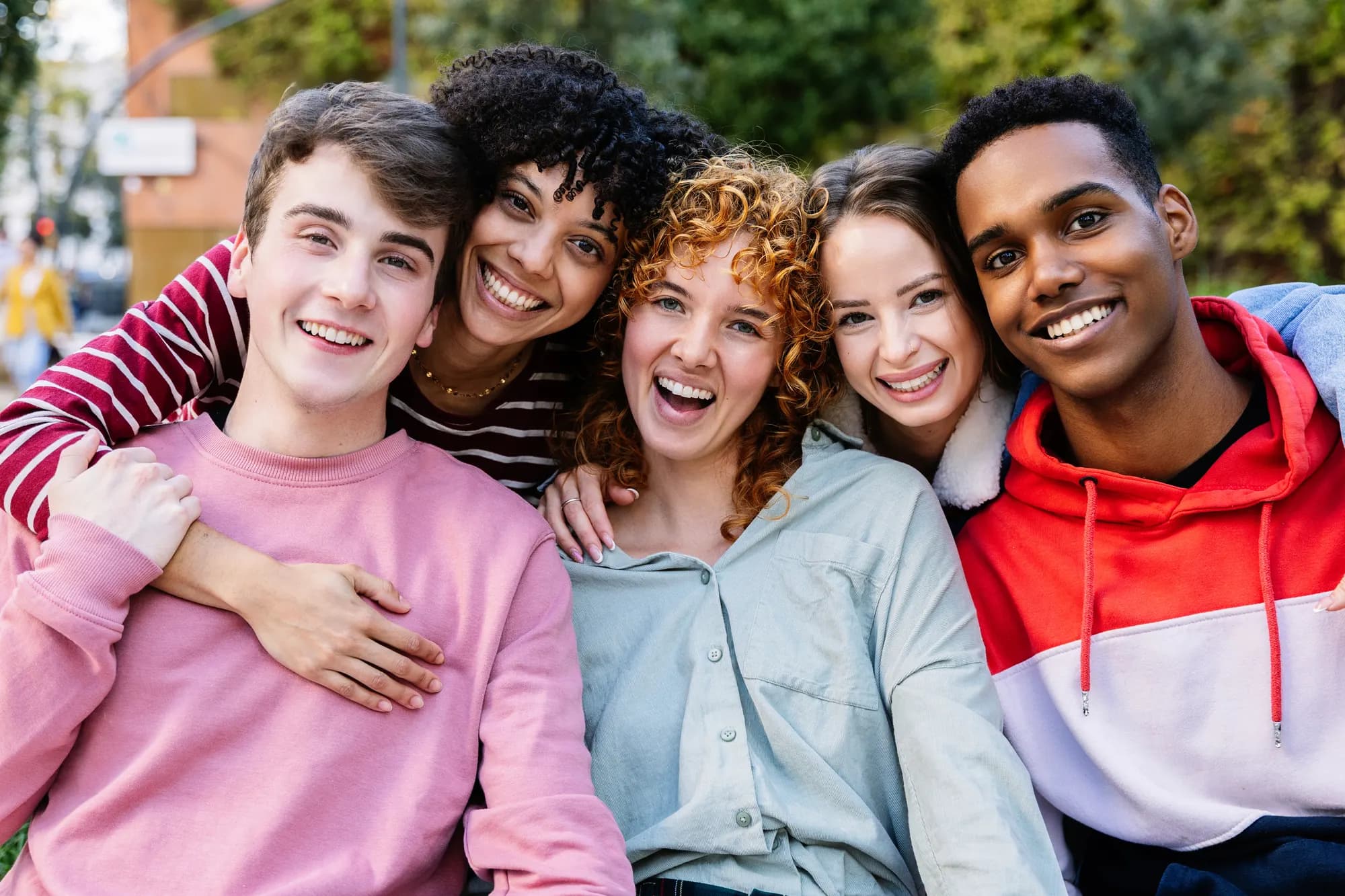 Five young people with their arms round each other, smiling at the camera